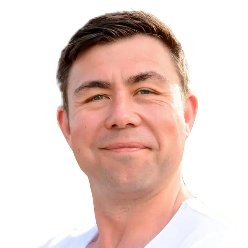 Smiling man with short dark hair, wearing a white shirt, looking approachable and warm.